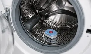 Una tab per lavastoviglie posizionata nel cestello di una lavatrice per la pulizia.