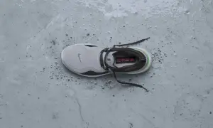 Scarpa da running Nike grigia, bagnata e sporca, pronta per essere messa in asciugatrice per un rapido recupero.