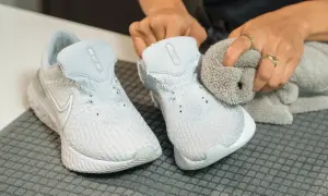 Hands cleaning light blue Nike sneakers with a grey cloth.