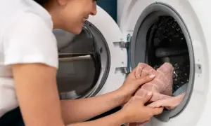 Donna sorride mentre pulisce la guarnizione della lavatrice, liberandola da ogni residuo di melma.