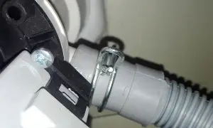 Dettaglio del tubo di scarico della lavatrice, fissato con fascetta metallica. Utile per capire come pulire il tubo di scarico della lavatrice.