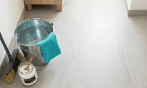 Secchio, scopa e barattolo di bicarbonato per pavimenti, pronti per una pulizia profonda.
