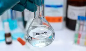 Un guanto blu tiene una beuta con ammoniaca, un composto chimico utile in molti processi industriali e di laboratorio.