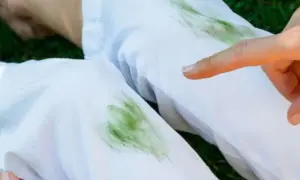 Un dito indica delle macchie d'erba su pantaloni bianchi, un piccolo disastro dopo una giornata all'aperto.