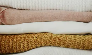 Pile di maglioni color pastello e ocra. Scopri come togliere elettricità dai vestiti per un comfort ottimale.