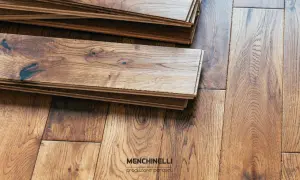 Tavole di parquet in legno grezzo, pronte per il trattamento. La venatura del legno è ben visibile, con nodi scuri che aggiungono carattere.