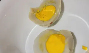 Uova sode tagliate a metà in una ciotola bianca, con tuorli gialli brillanti. La puzza di uovo marcio in casa è innegabile.