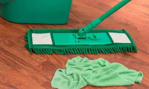 Mocio verde e secchio su pavimento in legno, pronti per pulire con ammoniaca per pavimenti.