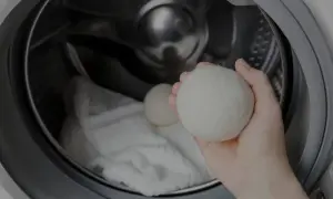 Mano che tiene una pallina per lavatrice, pronta per essere inserita nel cestello con il bucato. Scopri come si usa per un bucato più morbido.