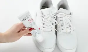Mano con tubetto di crema per scarpe bianche, pronto a pulire le sneakers. Un metodo efficace per far tornare come nuove le tue scarpe bianche.