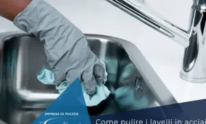 Mano con guanto grigio pulisce lavello in acciaio con panno azzurro. Scopri come pulire il lavello in acciaio dal calcare.