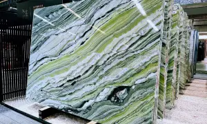 Lastre di marmo verde di prato con venature bianche e nere, esposte in un magazzino.