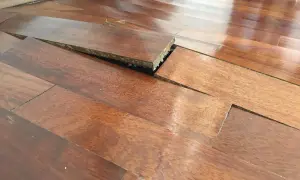 Parquet sollevato e deformato, con evidenti macchie di umidità che hanno compromesso le doghe.