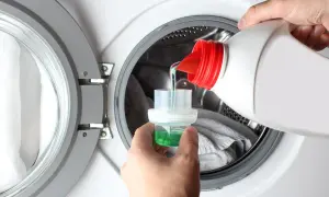 Versare il detersivo liquido nel tappo dosatore, un passo fondamentale per sapere come mettere la lavatrice e ottenere un bucato pulito.