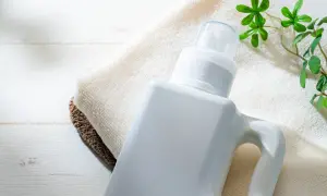 Flacone bianco di detersivi ecologici altroconsumo su asciugamani, con foglioline verdi.
