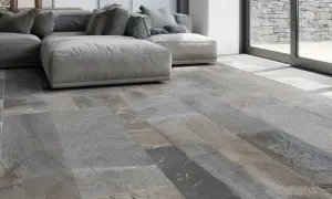 Pavimento in pietra di Luserna, grigio e variegato, con un divano moderno. Ideale per chi cerca consigli su come pulire la pietra di Luserna.