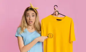 Ragazza sorpresa scopre macchie di detersivo sui vestiti con una lente d'ingrandimento.