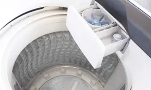 Cassetto detersivo lavatrice aperto, mostra come usare il detersivo liquido. La vaschetta è pronta per il bucato.