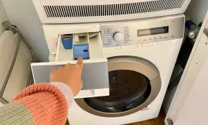 Mano indica il cassetto della lavatrice, dove si mette il detersivo. Forse l'ammorbidente fa male ai tessuti, meglio evitare.