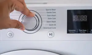 Mano che gira la manopola della lavatrice per scegliere il programma. La lavatrice usa acqua calda o fredda a seconda del ciclo selezionato.
