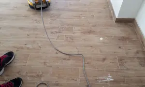 Macchina lucidatrice in azione per rimuovere la patina bianca sul pavimento in gres effetto legno.