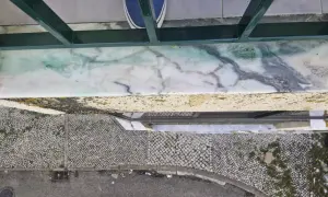 Come togliere la vernice dal marmo: una macchia verde su un davanzale di marmo, con scarpe blu in primo piano.