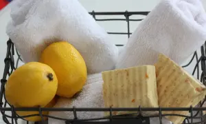 Cesto con sapone al limone fatto in casa, limoni freschi e morbidi asciugamani bianchi.