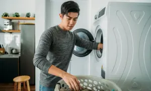 Uomo mette panni nella lavatrice, forse aggiungerà ammoniaca lavatrice per un bucato più fresco.