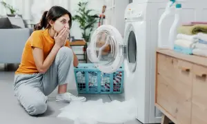 Donna sorpresa con le mani sulla bocca, la lavatrice perde schiuma. Scopri come eliminare la schiuma dalla lavatrice.
