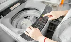 Mani che impostano la lavatrice per un lavaggio delicato, pensando a come lavare le Timberland in lavatrice per farle tornare come nuove.