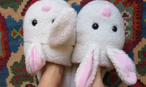 Pantofole a forma di coniglio bianco con orecchie rosa, pronte per essere lavate in lavatrice.