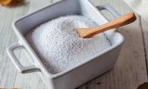 Piatto bianco con percarbonato di sodio e cucchiaio di legno. Informarsi sui percarbonato di sodio controindicazioni prima dell'uso.