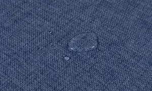 Gocce d'acqua su tessuto blu, dimostrando l'efficacia del lavaggio antimacchia in lavatrice.