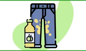 Un flacone di detersivo accanto a un paio di pantaloni con una macchia d'olio gialla.