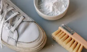 Scarpe bianche in pelle pronte per essere pulite con bicarbonato e una spazzola.