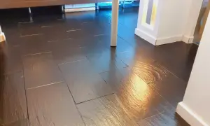 Pavimento in bollettonato di marmo scuro, lucido e riflettente, con un pilastro bianco al centro.