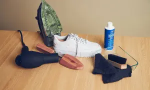 Attrezzi per pulire scarpe di tela bianche ingiallite: ferro da stiro, asciugacapelli, calzature, prodotto per pulizia, spazzola e panni.