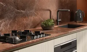 Piano cottura a gas su top in marmo rosso, con lavello nero, rubinetto moderno e bollitore Smeg. Le cucine con pavimento cotto hanno un fascino rustico.