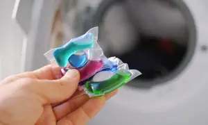 Mani che tengono capsule colorate per lavatrice. Attenzione, le capsule rovinano la lavatrice se usate impropriamente.