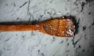 Un cucchiaio di legno con residui di sapone di Marsiglia, pronto per pulire pavimenti in marmo.