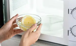 Mani inseriscono una ciotola con acqua e limone nel microonde, un metodo semplice per pulire l'elettrodomestico.