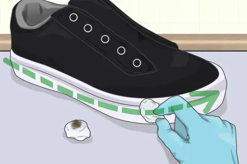 Guanto blu pulisce la suola bianca di una scarpa nera con un batuffolo di cotone. Ecco come pulire la suola delle scarpe per farle sembrare nuove.