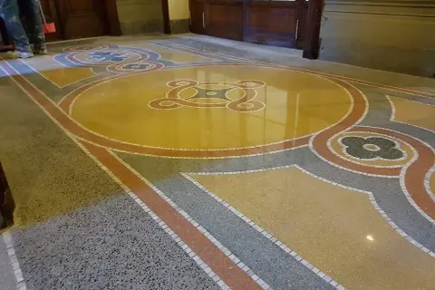 Pavimenti marmo anni 70 con motivi geometrici e floreali in giallo, grigio e rosso. Un restauro che riporta alla luce la bellezza del passato.
