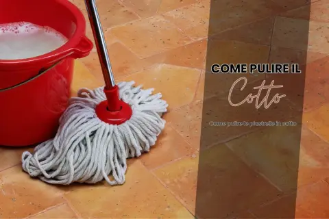 Secchio rosso con acqua saponata e uno straccio sul pavimento in cotto. Guida su come pulire pavimenti esterni ruvidi in cotto.