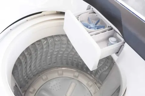 Cassetto aperto della lavatrice, mostra dove mettere detersivo lavatrice. Si vedono i vani per i prodotti e la ventola per la distribuzione.