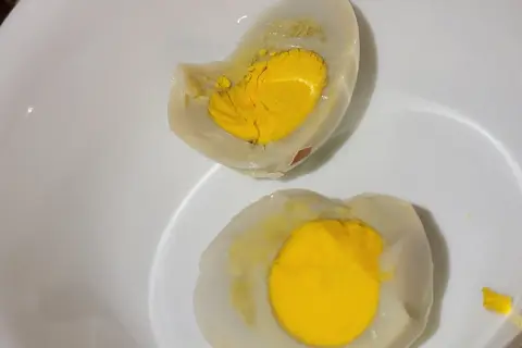 Uova sode tagliate a metà in una ciotola bianca, con tuorli gialli brillanti. La puzza di uovo marcio in casa è innegabile.