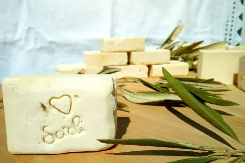 Sapone artigianale, frutto della saponificazione olio di oliva, con decorazione a cuore e scritta "Sich". Foglie d'ulivo completano la scena.