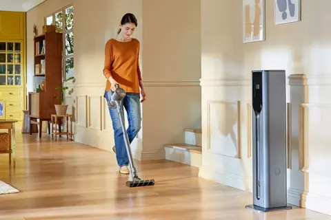 Donna aspira il pavimento in legno lucido, mostrando un modo semplice per pulire il cotto.