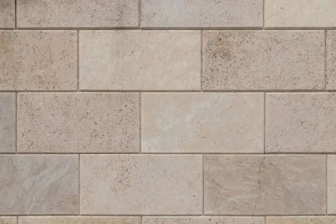 Dettaglio di un pavimento in trachite, con blocchi rettangolari di pietra chiara, alcuni con venature naturali e piccole inclusioni.