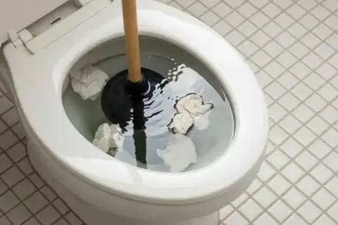 Strofinaccio nel water, con carta che galleggia. Il water non porta via la carta, creando un blocco.